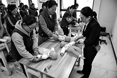 湖南长沙市的职业培训学校老师在育婴员培训班上为学员们讲解抚触婴儿的手法及注意事项。   新华社发